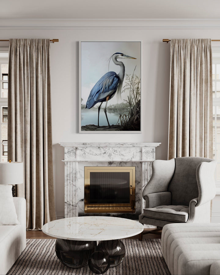 Framed canvas wall art of a blue heron in a coastal setting above a marble fireplace.