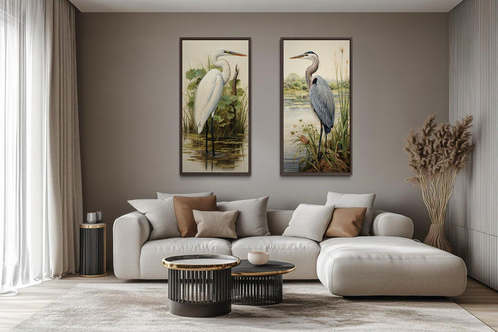 Set of two framed canvas prints featuring a blue heron and a white egret in a modern living room.