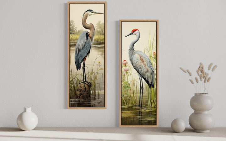 Set of two tall vertical canvas prints featuring a blue heron and a sandhill crane in marsh settings.