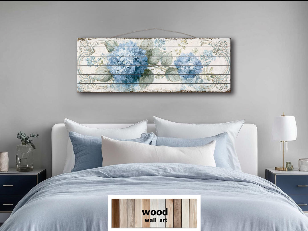 Blue hydrangea floral art on distressed wood planks hanging above a bed in a modern bedroom.