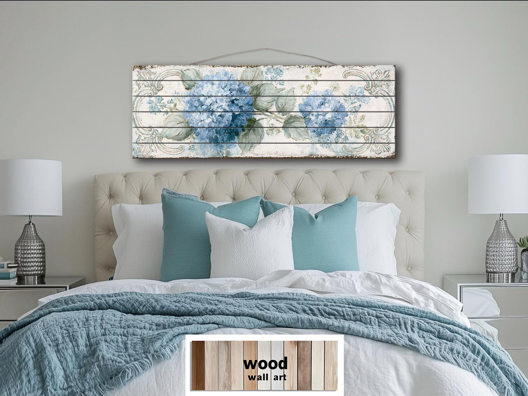 Blue hydrangea floral art printed on horizontal distressed wood planks hanging above a bed.