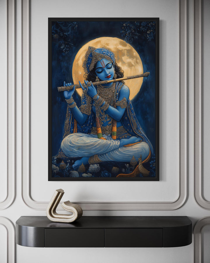 Blue Krishna playing a flute under a full moon, framed canvas wall art above a black console table.