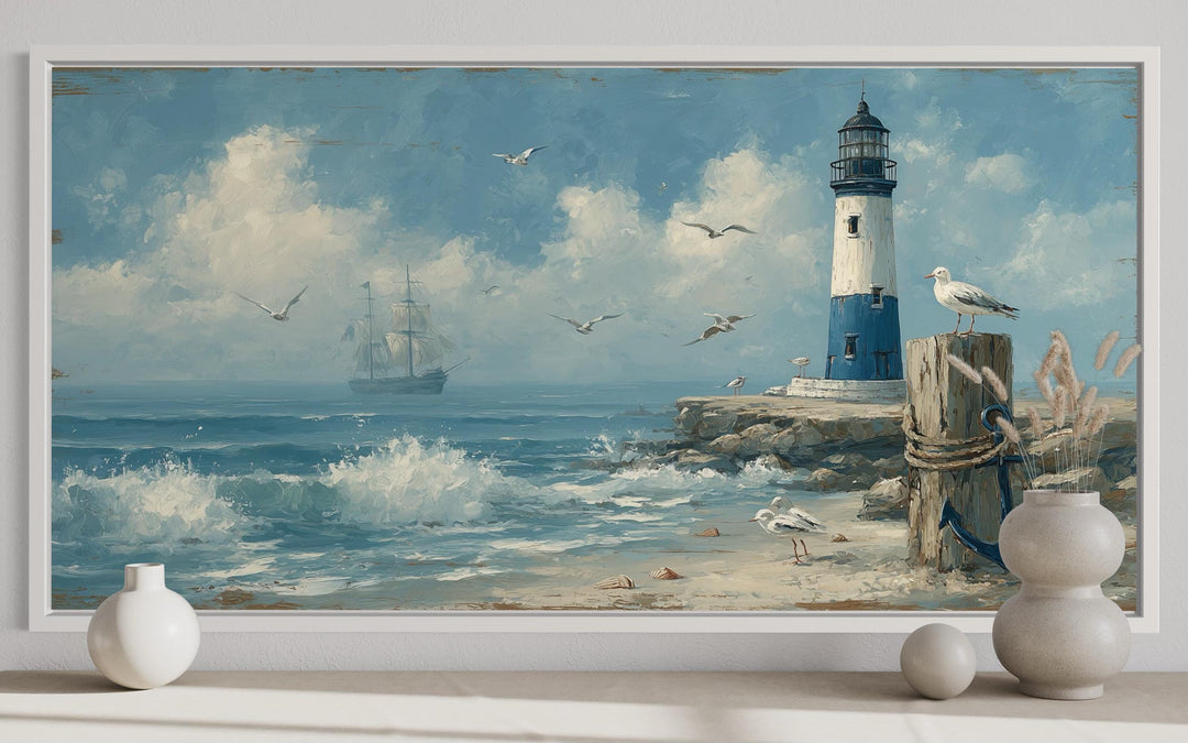 Framed blue lighthouse seascape wall art with a sailboat, seagulls, and waves on a sandy beach.