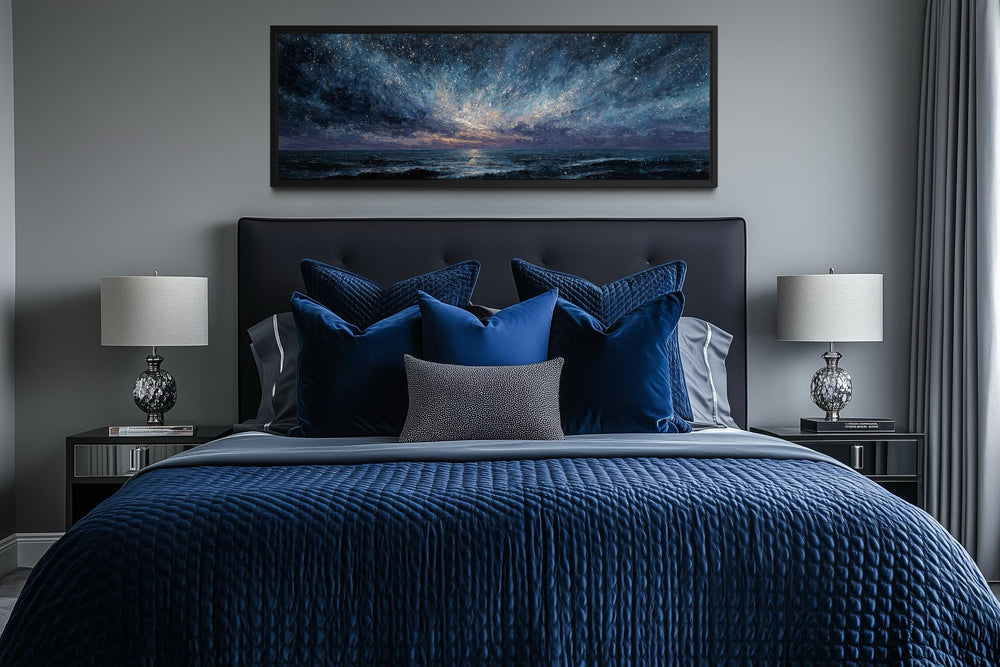 Panoramic moody seascape canvas print in navy and purple tones hanging above a modern bed.