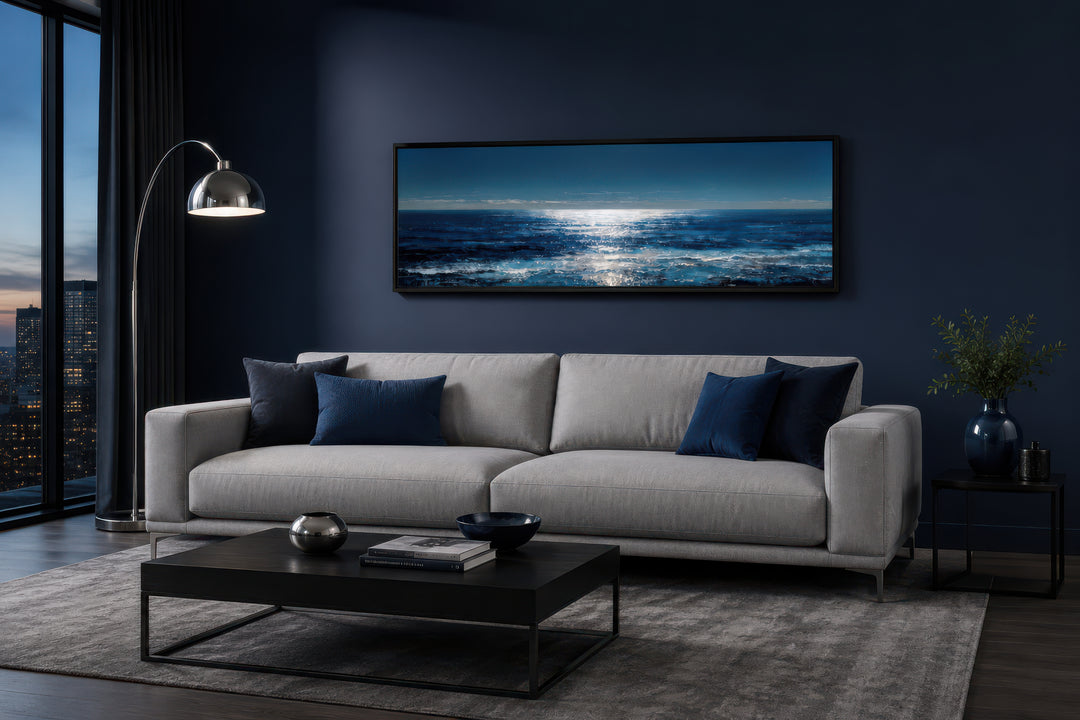 Long horizontal seascape wall art featuring a blue and silver ocean horizon over a gray sofa.