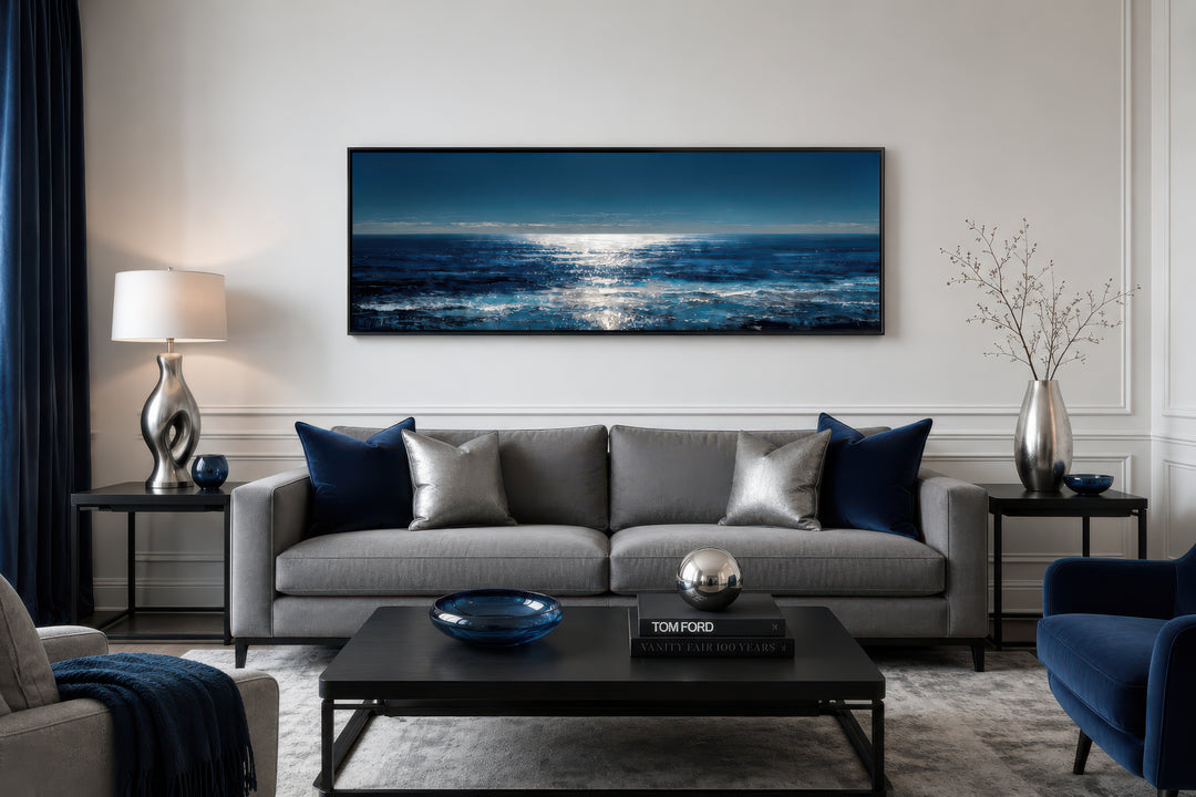 Long horizontal seascape wall art featuring a blue and silver ocean horizon over a gray sofa.