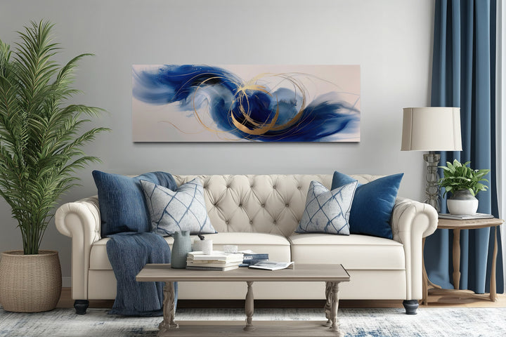 Blue, white, and gold minimalist abstract narrow horizontal wall art above a beige sofa.
