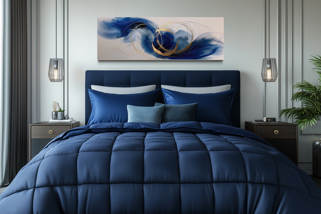 Blue, white, and gold minimalist abstract narrow horizontal wall art hanging above a navy blue bed.