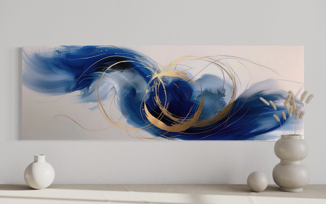 Narrow horizontal abstract wall art with blue, white, and gold brushstrokes above a console table.
