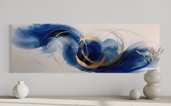 Narrow horizontal abstract wall art with blue, white, and gold brushstrokes above a console table.