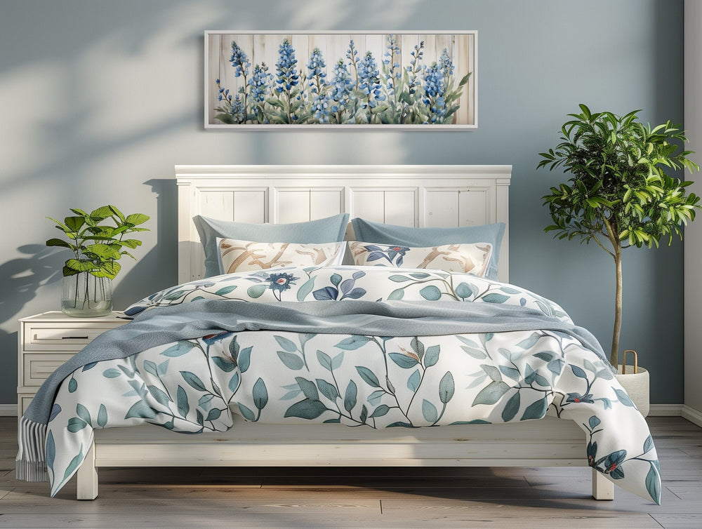 Blue wildflowers horizontal framed canvas wall art hanging above a white bed with floral bedding.