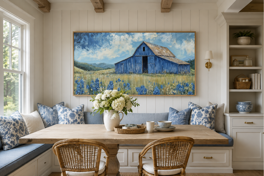 Rustic framed canvas wall art of a blue barn in a field of bluebonnets above a dining nook.