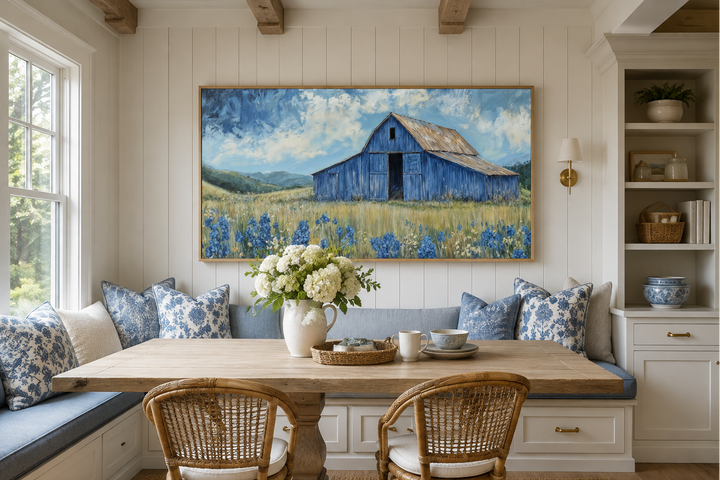 Rustic framed canvas wall art of a blue barn in a field of bluebonnets above a dining nook.