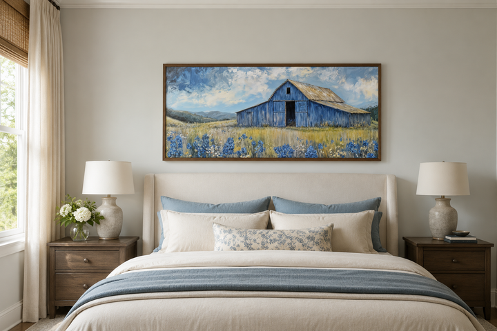 Blue barn and bluebonnets rustic framed canvas wall decor hanging above a bed in a neutral bedroom.
