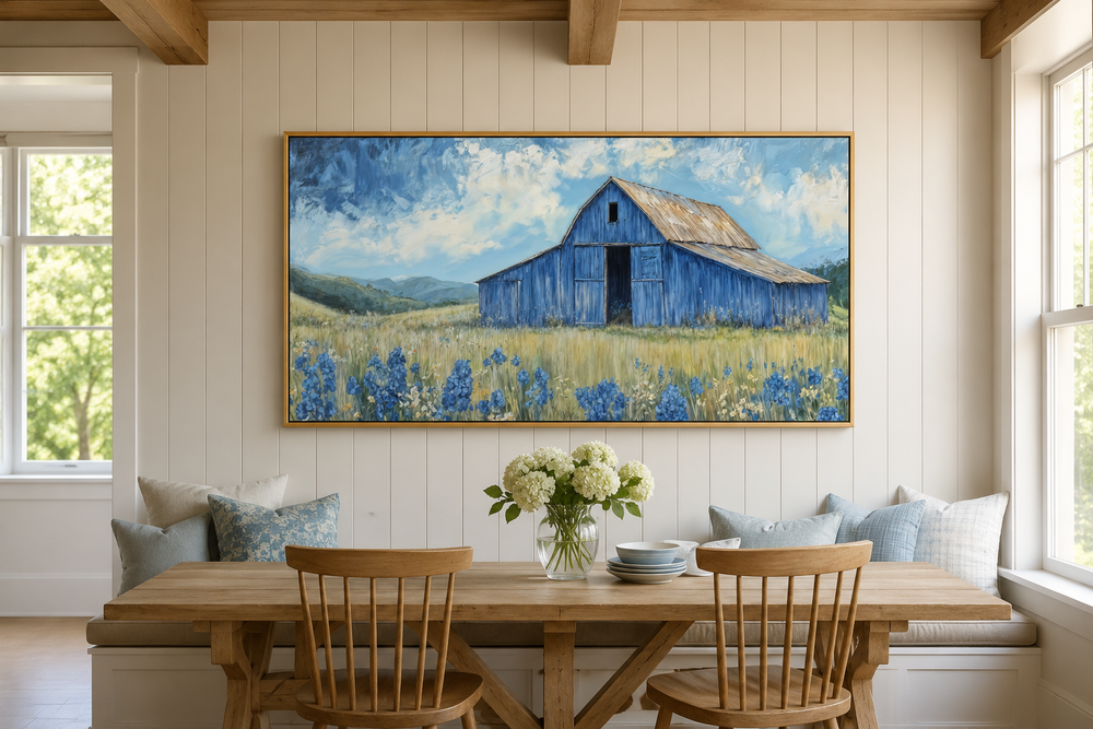 Rustic framed canvas wall art of a blue barn and bluebonnets in a field above a dining table.