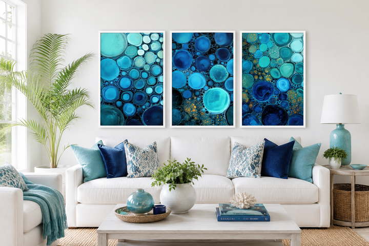 Three-panel abstract canvas set featuring blue, aqua, and navy bubble patterns over a white sofa.