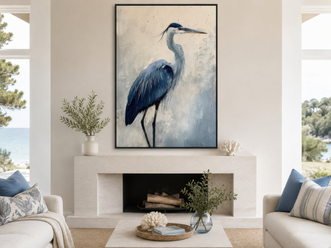 Vertical framed canvas wall art of an abstract blue heron painting above a modern fireplace.