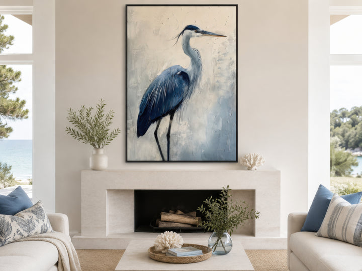 Vertical framed canvas wall art of an abstract blue heron painting above a modern fireplace.