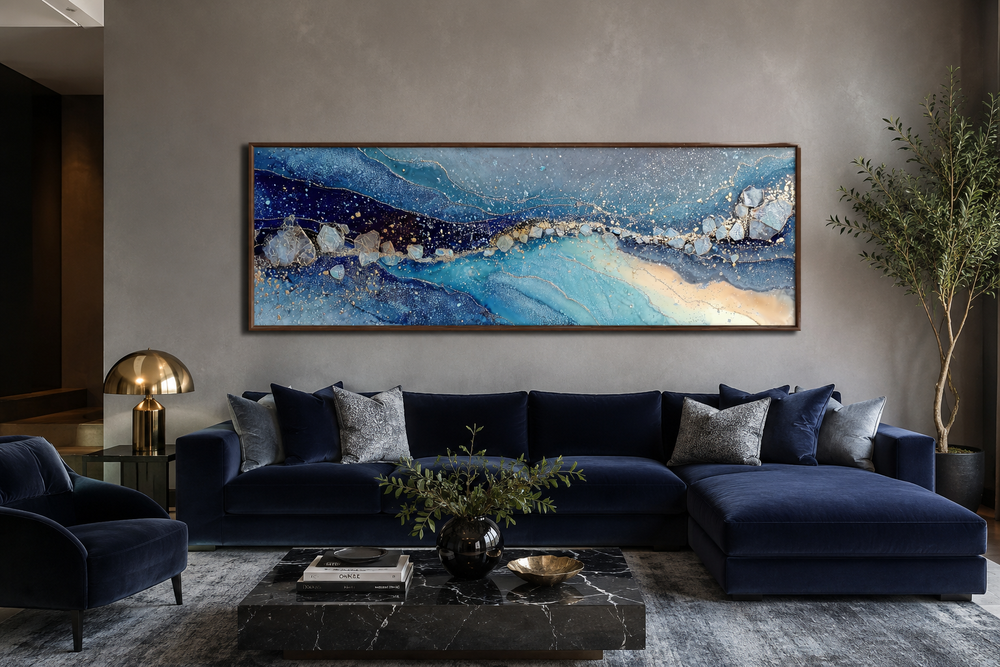 Modern long horizontal blue and navy abstract canvas art hanging above a dark blue velvet sofa.
