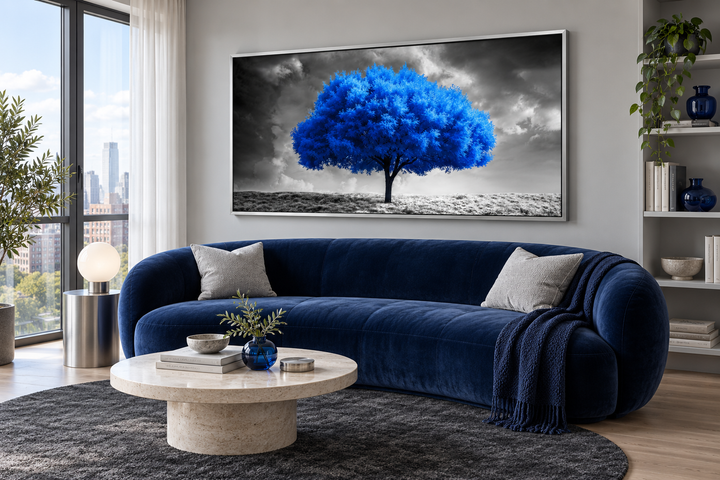 Framed canvas wall art of a vibrant blue tree against a black and white landscape in a living room.