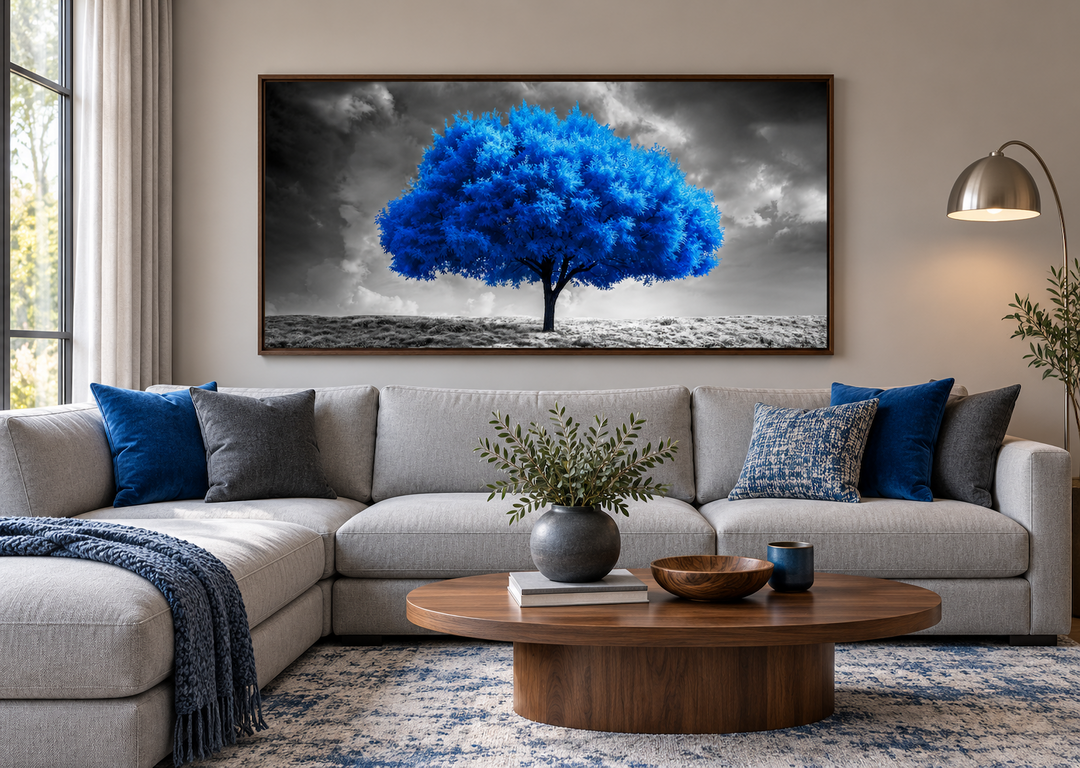 Blue tree on black and white background framed canvas wall art above a gray sectional sofa.