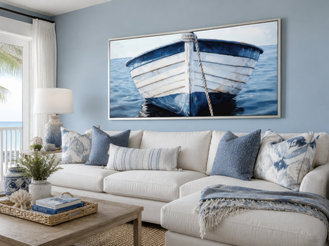Rustic blue and white boat canvas wall art in a coastal living room above a white sectional sofa.