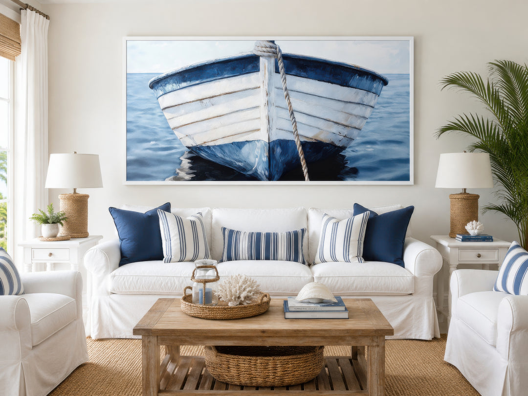 Large framed canvas print of a rustic blue and white boat on water above a white sofa.