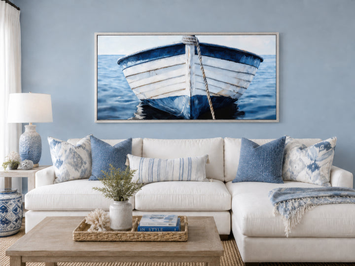 Rustic blue and white boat wall art framed above a white sectional sofa in a coastal living room.