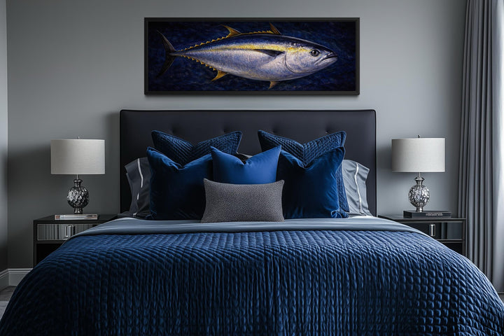 A long horizontal canvas painting of a bluefin tuna hangs above a bed with navy blue bedding.