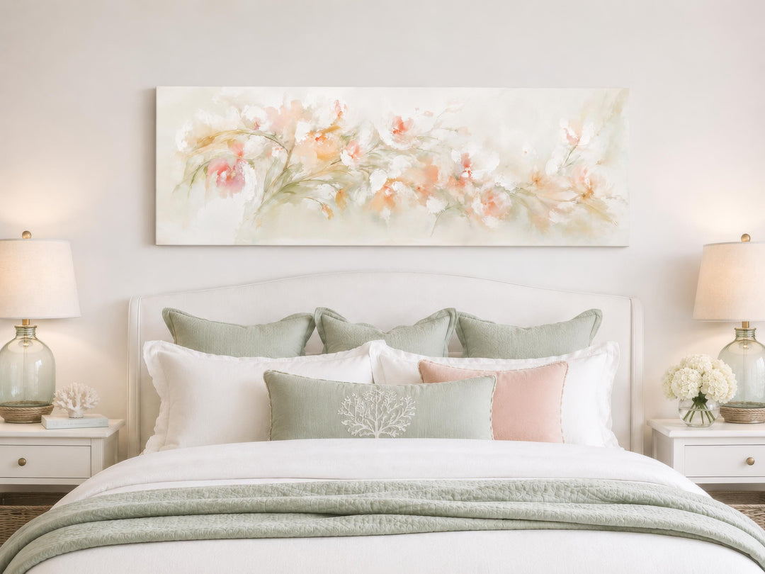 Long horizontal watercolor canvas painting of blush pink and peach flowers above a white bed.