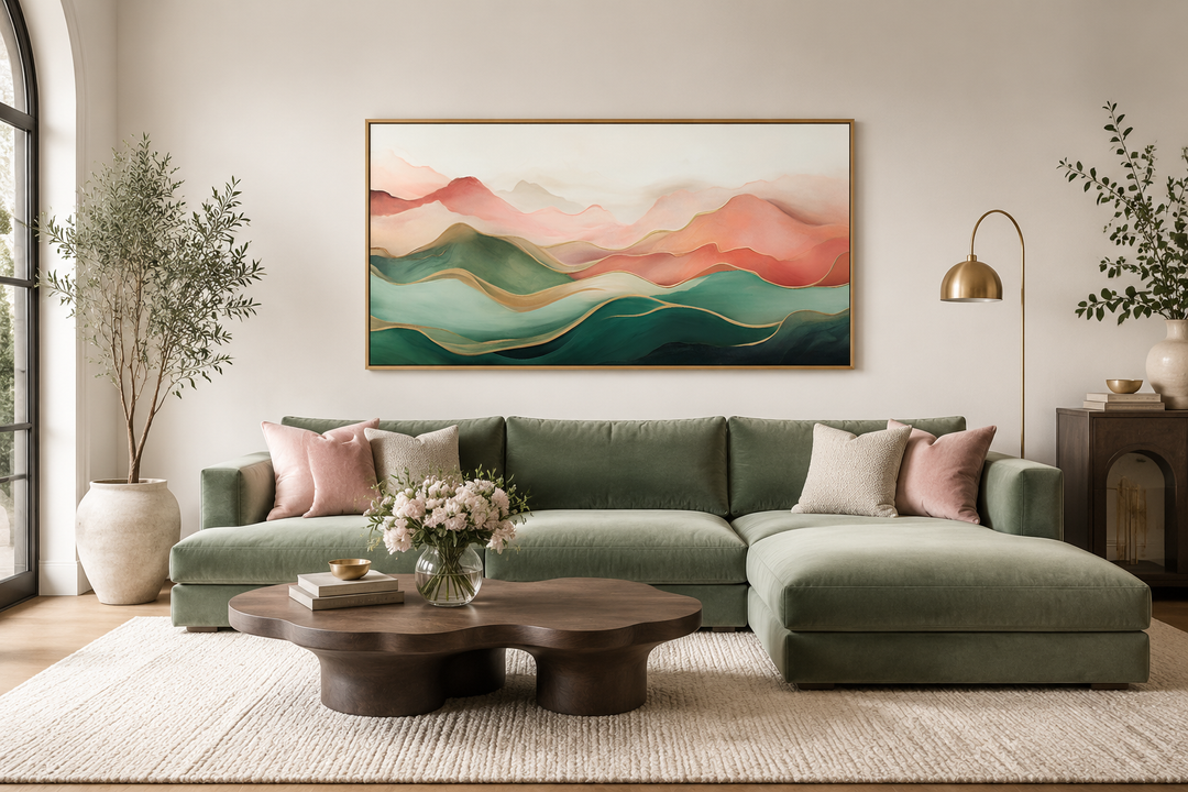 Framed canvas print of an abstract mountain landscape in blush pink and green above a green sofa.