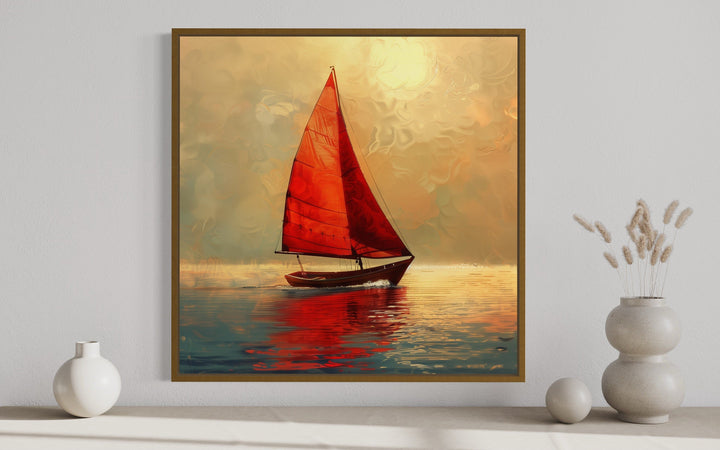 Framed canvas wall art of a boat with red sails on calm water during a golden sunset.