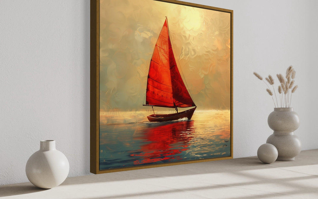 Framed canvas wall art of a boat with red sails on calm water during a golden sunset.