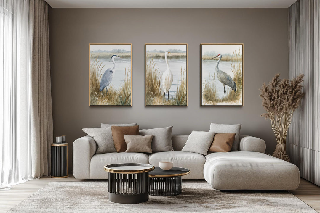 Three vertical canvas prints of a heron, egret, and crane in a neutral boho coastal living room.