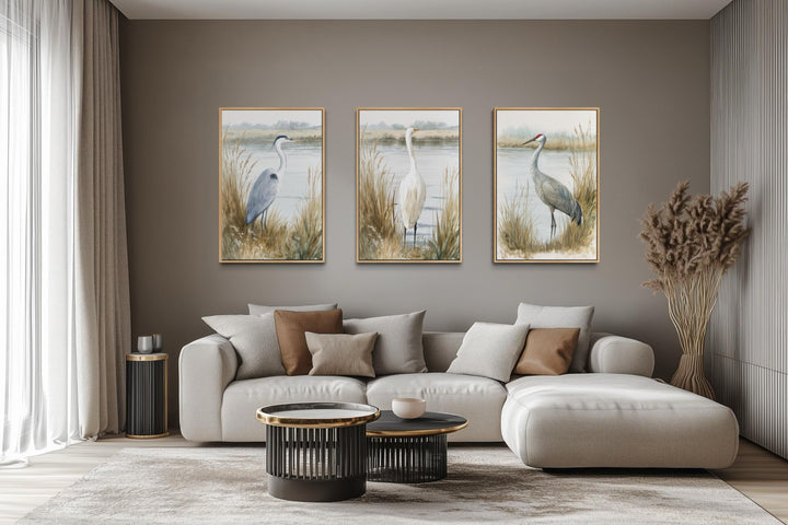 Three vertical canvas prints of a heron, egret, and crane in a neutral boho coastal living room.