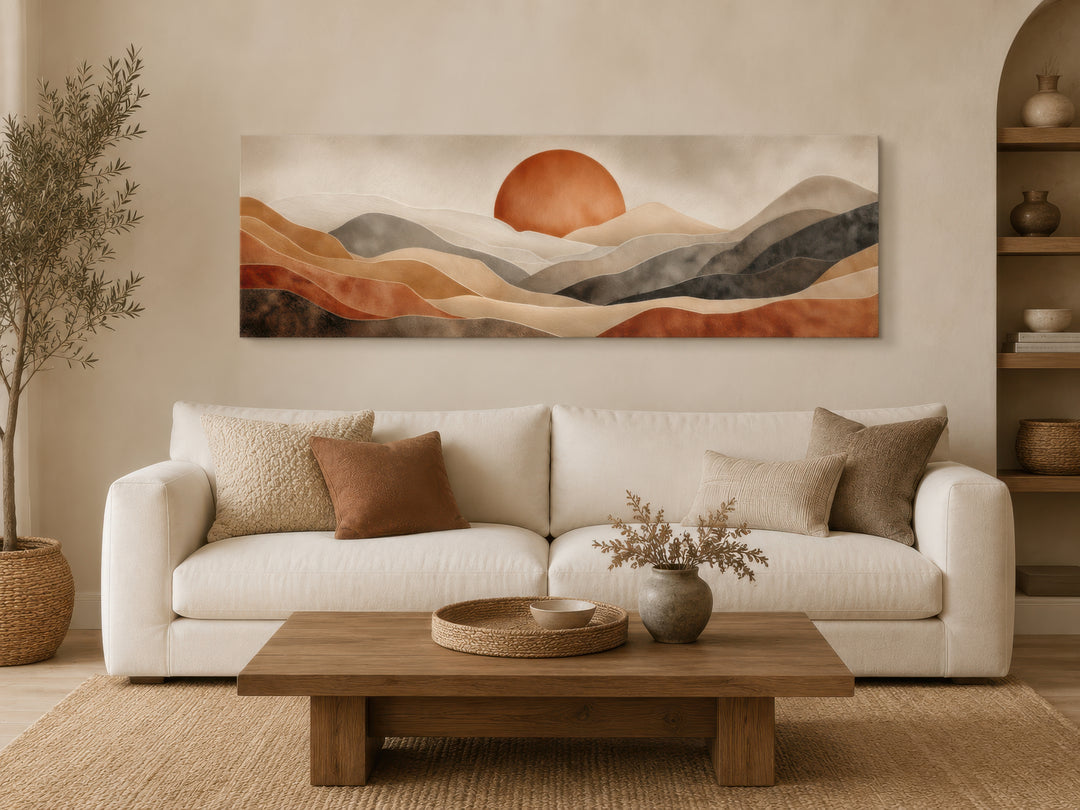 Long horizontal boho desert wall art with terracotta sun and hills above a white sofa.