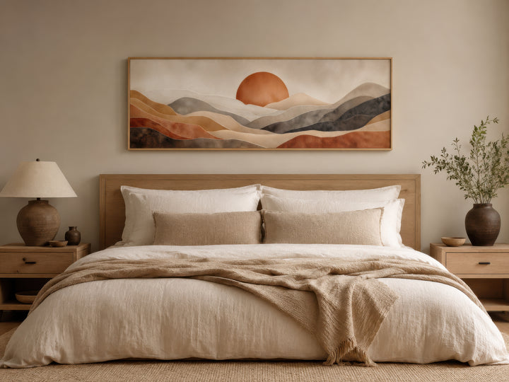 Long horizontal boho desert wall art with a terracotta sun and hills above a neutral-toned bed.