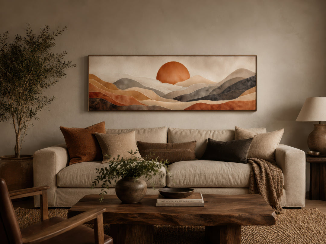 Long horizontal canvas print of a boho desert landscape with a terracotta sun above a sofa.