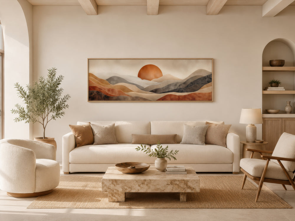 Long horizontal boho desert canvas print with terracotta sun and hills above a cream sofa.