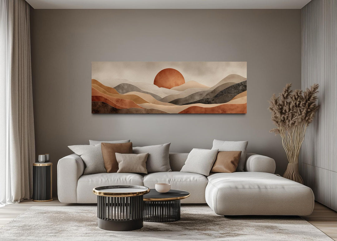Boho desert wall art featuring a terracotta sun and rolling hills above a modern living room sofa.