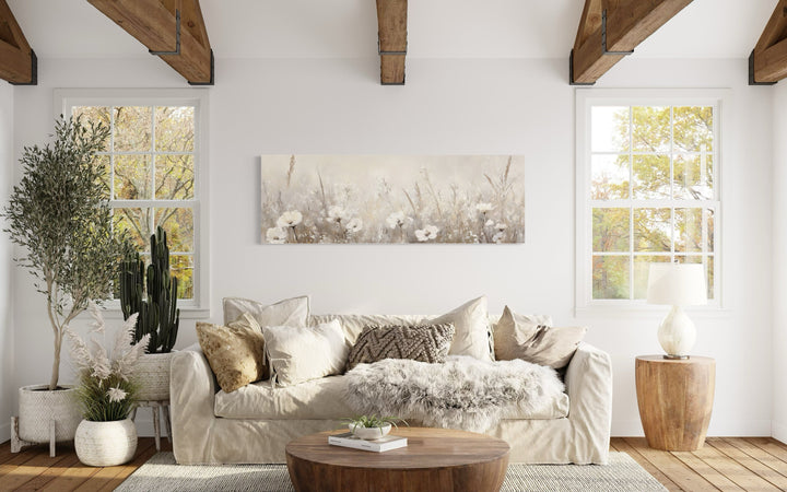 Horizontal canvas wall art featuring a neutral wildflower field above a cream-colored sofa.