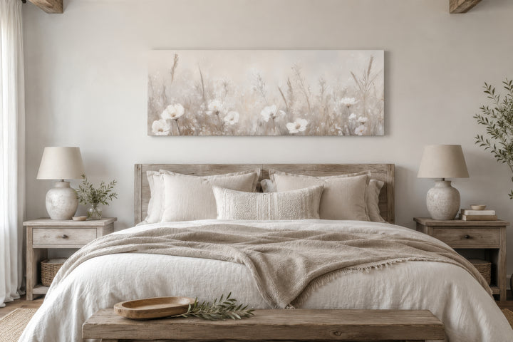 Horizontal canvas wall art of neutral wildflowers in a field hanging above a farmhouse-style bed.