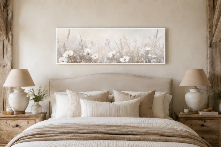 Horizontal wall art of neutral wildflowers in a white frame hanging above a farmhouse-style bed.
