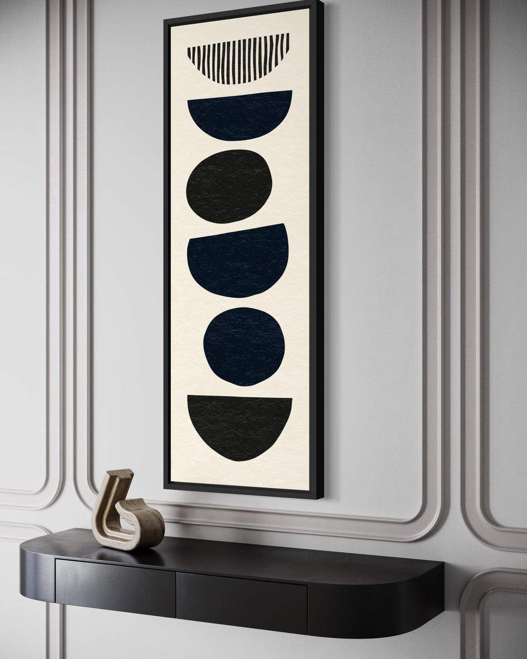 Boho stacked stones canvas wall art in a tall narrow black frame above a modern black console table.