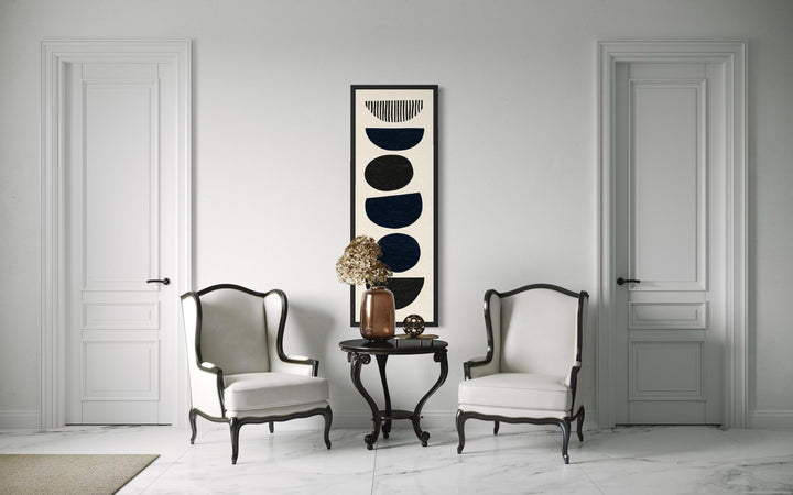 Tall narrow canvas wall art featuring black stacked geometric stone shapes on a neutral background.