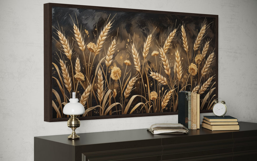 Framed canvas print of a boho wheat field in brown and beige tones above a dark wood sideboard.