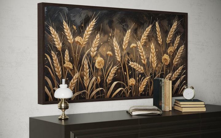 Framed canvas print of a boho wheat field in brown and beige tones above a dark wood sideboard.