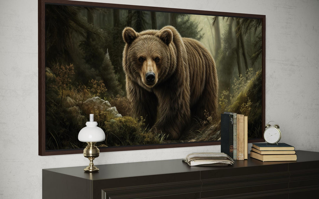 A framed canvas print of a majestic brown bear walking through a misty forest above a dark dresser.