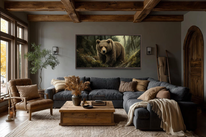 A large canvas print of a brown bear in a forest hangs above a sofa in a rustic living room.
