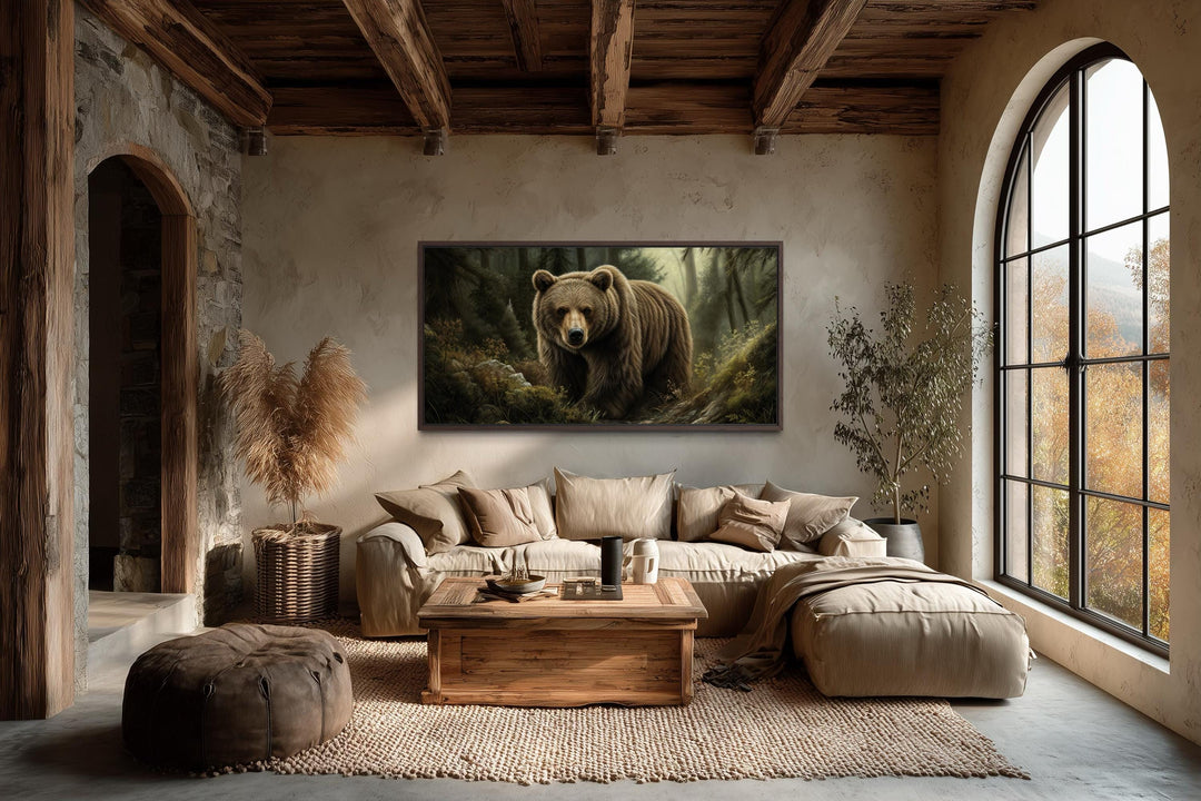 A large canvas print of a brown bear in a forest hangs in a rustic living room with wooden beams.